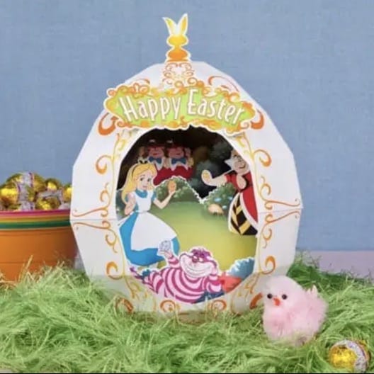 A paper cut out diorama of Alice in the Red Queen's garden with the Cheshire cat and Tweedle Dee and Tweedle Dum