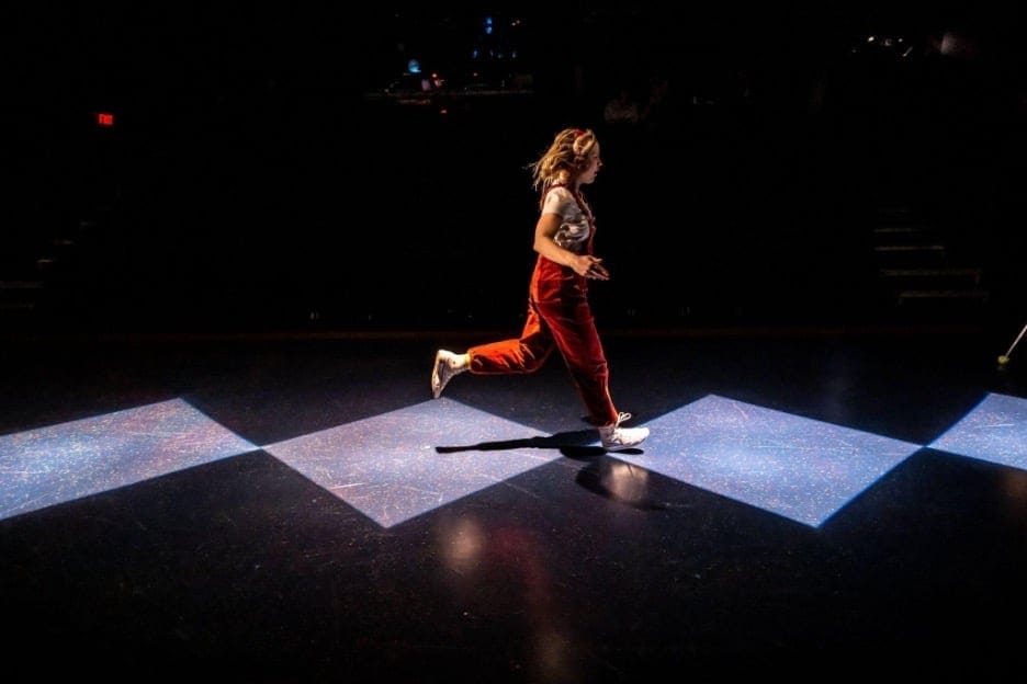 Image of Alice, running across the stage. This photo is taken from Bad Hat Theatre's unique adaptation of Lewis Carroll's Alice in Wonderland.