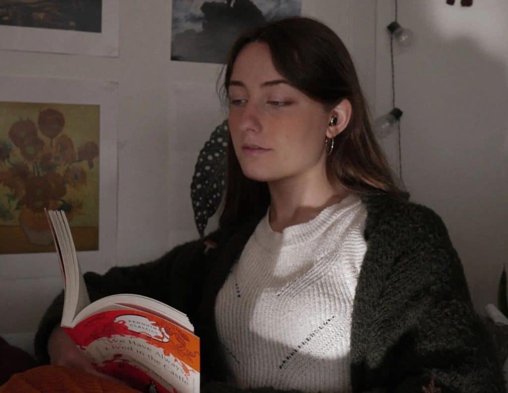Image of Booktuber, TheBookLeo, she is reading a paperback book called: "We Have Always Lived in the Castle".