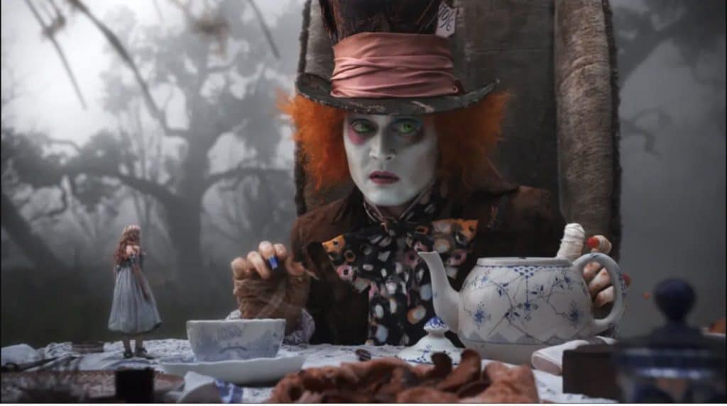 Johnny Depp's portrayal of The Mad Hatter, sitting at a table, pouring a cup of tea, next to a very small Alice. From Tim Burton's 2010 reimagining of Lewis Carroll, and Disney's Alice in Wonderland. 
