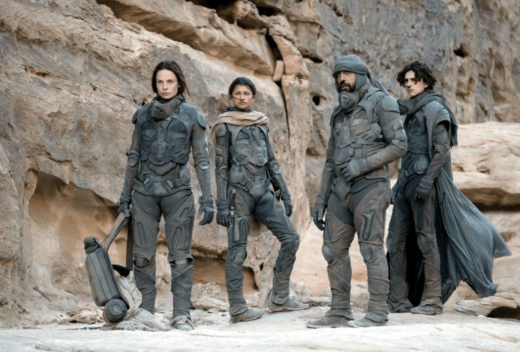 Still image of Timothee Chalamet as Paul Atreides, Rebecca Ferguson as Lady Jessica, Zendaya as Chani, and Javier Bardem as Stilgar from the 2021 Denis Villeneuve film "Dune". 