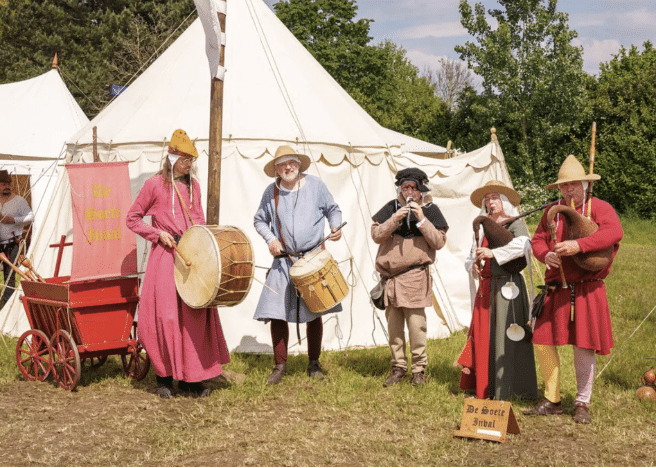 Image of the Dutch medieval band De Soete Inval in medieval peasant dress at a historical festival.
