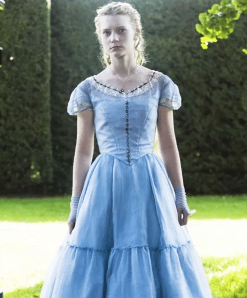 Still image of Mia Wasikowska as Alice Kingsleigh, wearing a blue dress, in the 2010 Tim Burton film "Alice in Wonderland".