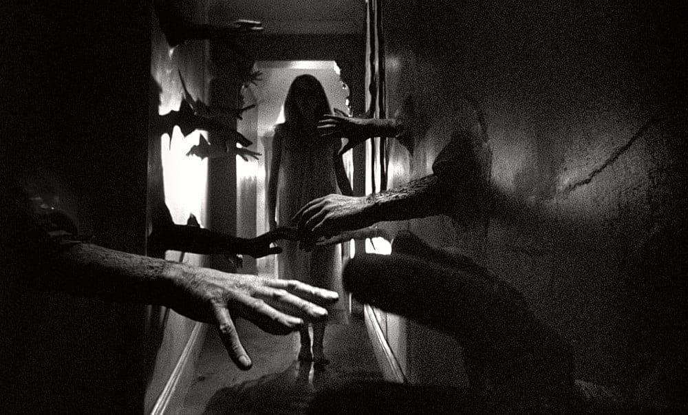 Black and white still image of Catherine Deneuve walking down a hallway with hands sticking out of the walls in the foreground from Roman Polanski's 1965 psychological horror thriller film "Repulsion".